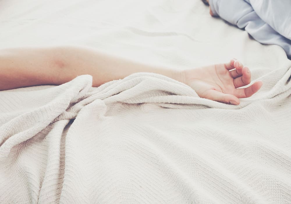 Main posée sur des draps en lin, lumière douce